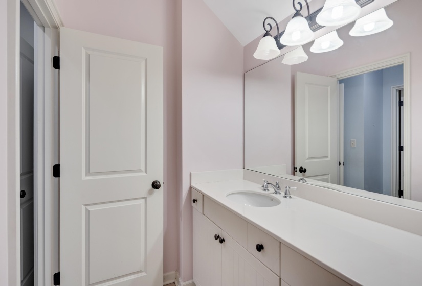 White vanity with integrated sink, chrome faucet, and expansive wall-mounted mirror