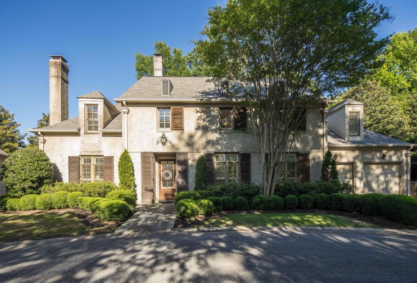 Traditional architecture featuring a stucco exterior with multiple gabled dormers, an attached two-car garage, and established landscaping