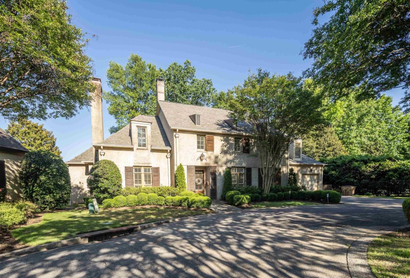 Stucco exterior with multiple chimneys, prominent dormer windows, and dark louvered shutters