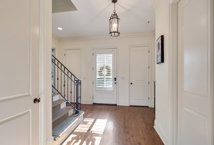 Foyer featuring wood-finish flooring, a traditional lantern pendant light, and a staircase with a wrought iron railing