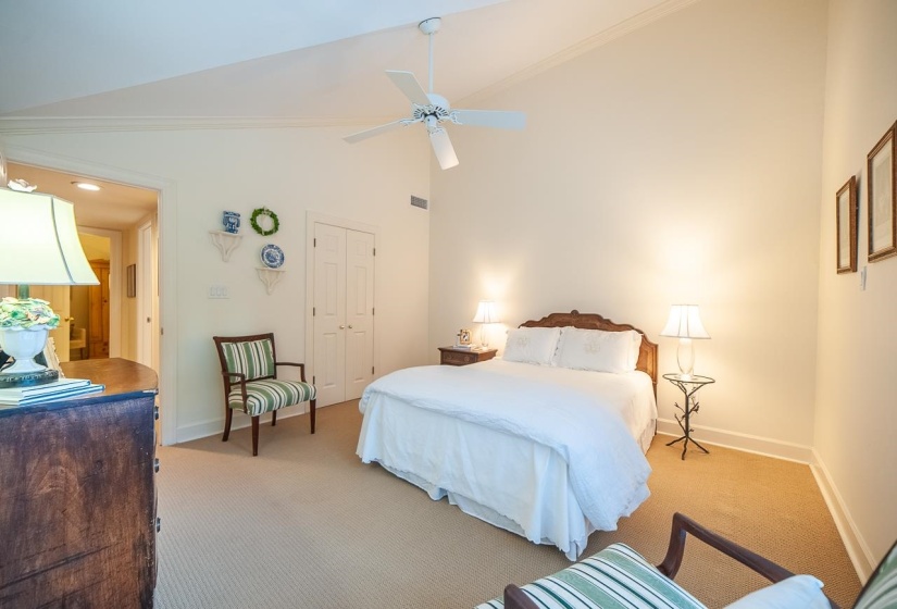 Bedroom with angled vaulted ceiling with a ceiling fan, neutral wall paint, and wall-to-wall carpeting and plantations shutter