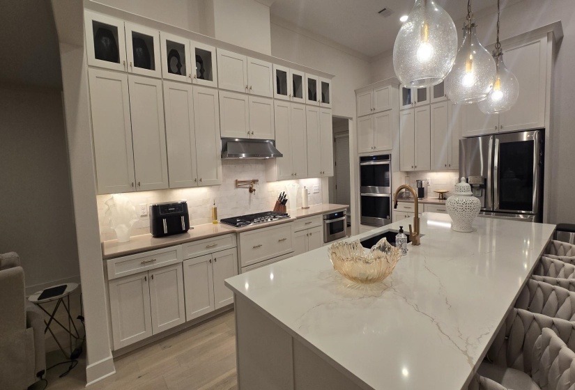 Gourmet kitchen featuring a large central island with seating, integrated sink, and pendant lighting