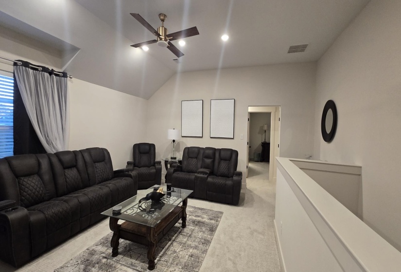 Carpeted living area featuring vaulted ceilings, a ceiling fan with integrated lighting, recessed lighting, and a balustrade