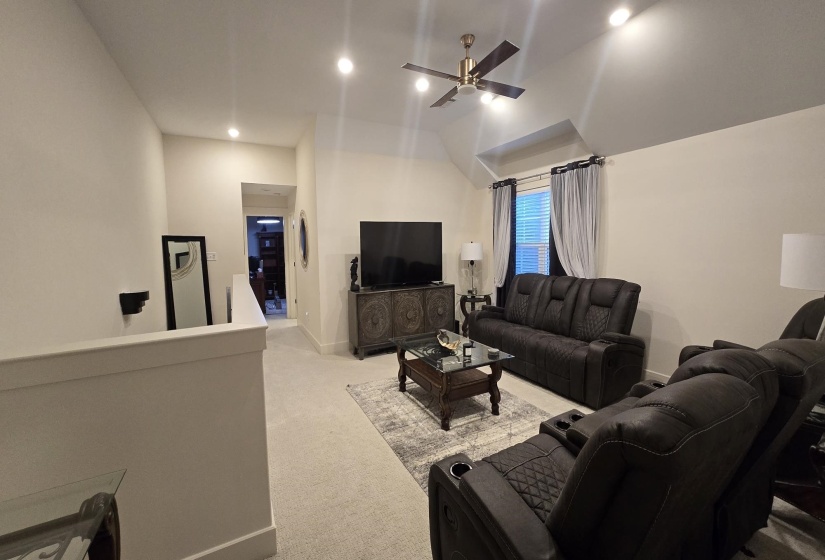 Spacious carpeted bonus room featuring a vaulted ceiling with a ceiling fan, recessed lighting, and a window with blinds