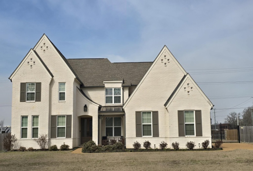 Traditional-style residence featuring a light brick exterior with dark shutters