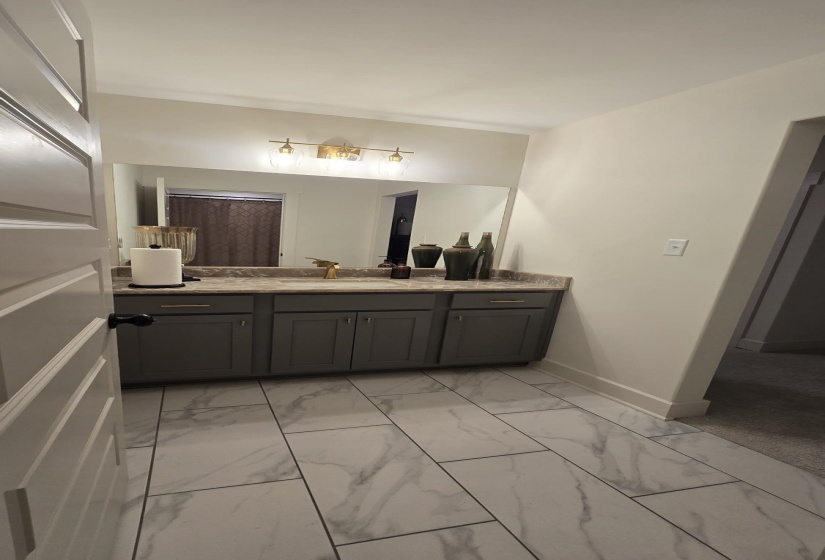 Vanity area featuring a gray cabinet with gold hardware, a stone-finish countertop, and a large mirror