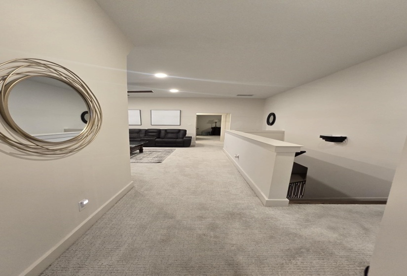 Carpeted hallway with white walls and recessed lighting