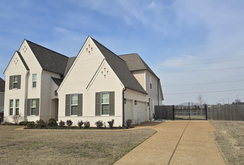 Two-story residence featuring light-colored brick facade with dark shutters and a dark shingle roof