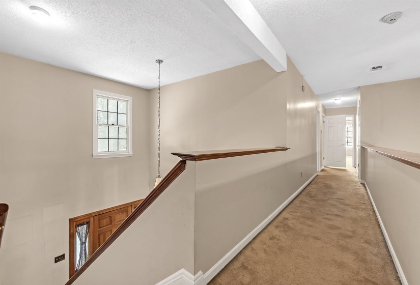 Upper-level hallway featuring neutral wall paint, carpet flooring, and white trim
