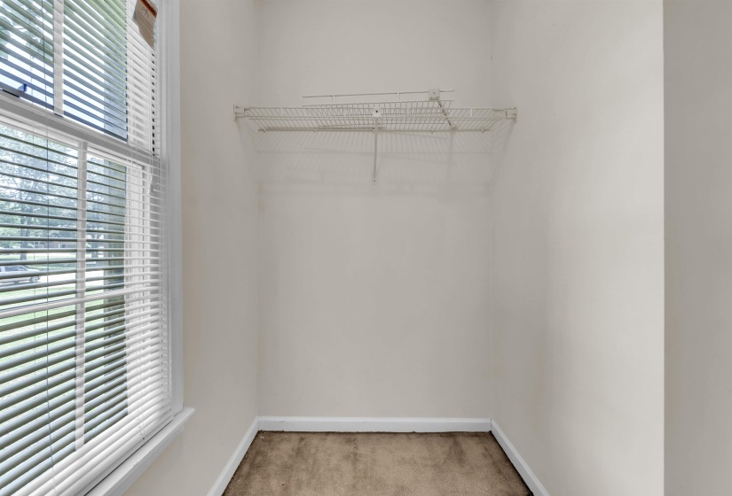 Recessed closet space featuring wire shelving, a window with horizontal blinds, and base molding