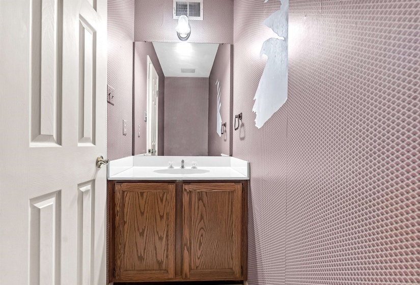 Vanity featuring a wood-finish cabinet, white countertop, and integrated sink with chrome faucet