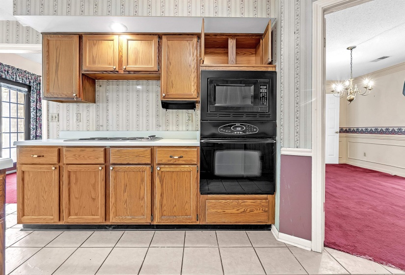 Kitchen featuring wood cabinetry, white countertops, built-in black microwave, and black wall oven