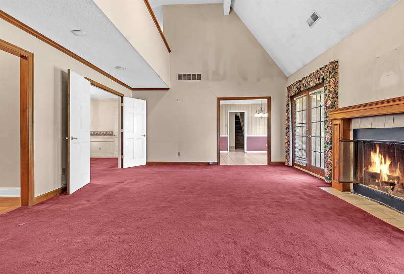 Spacious living area featuring a vaulted ceiling and a wood-burning fireplace with a tile hearth and wood mantel