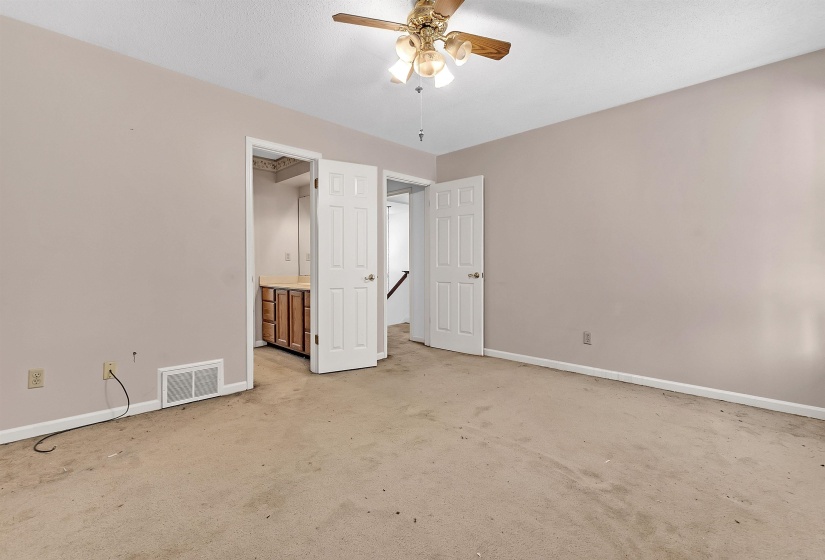 Spacious room featuring neutral painted walls, ceiling fan with integrated lighting, and carpeted flooring