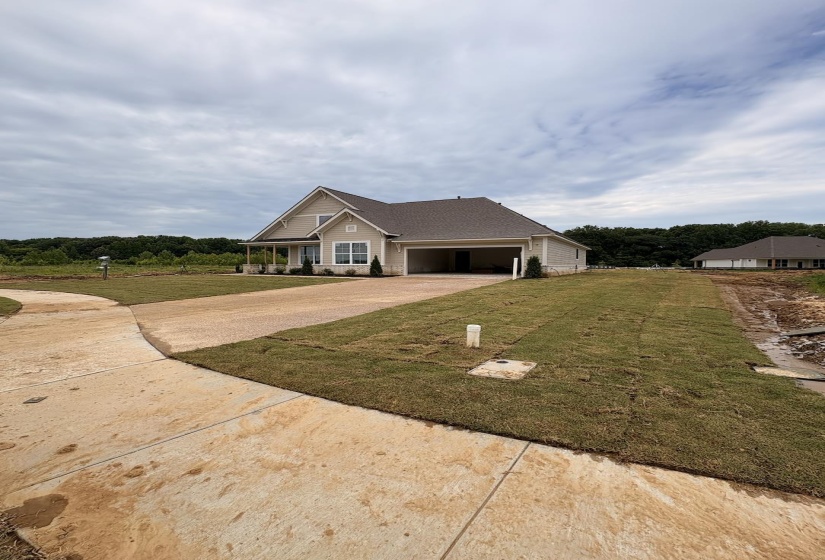 Single-story residence featuring a covered front porch, attached garage, concrete driveway, and newly laid sod