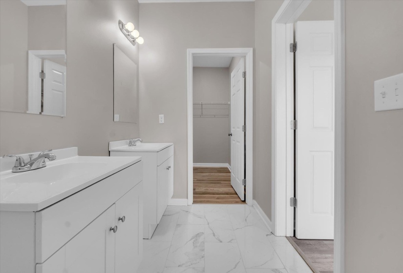 Bathroom featuring dual white vanities with integrated sinks, chrome faucets, and individual rectangular mirrors