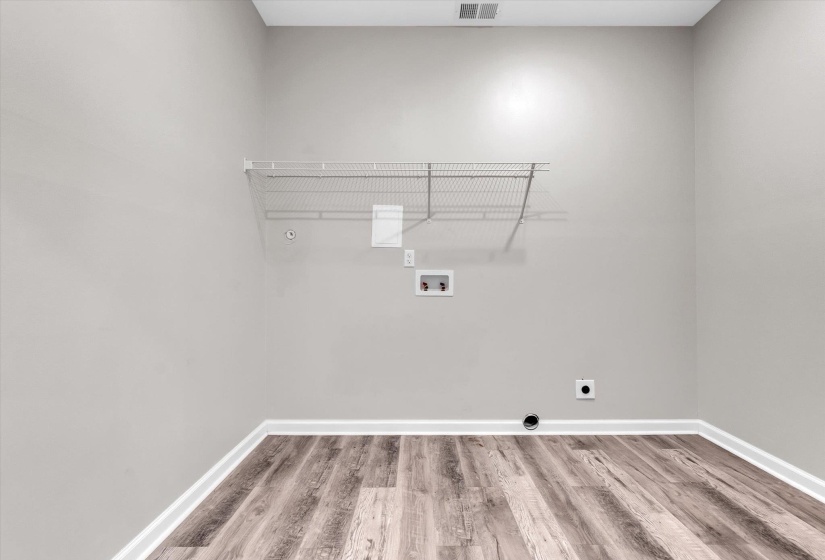 Laundry area featuring wood-finish flooring, light gray walls, white baseboards, and a wire shelving unit