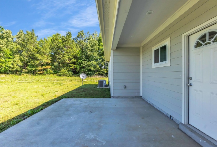 Concrete patio with a light gray exterior, white trim, and a prominent white entry door featuring an arched window