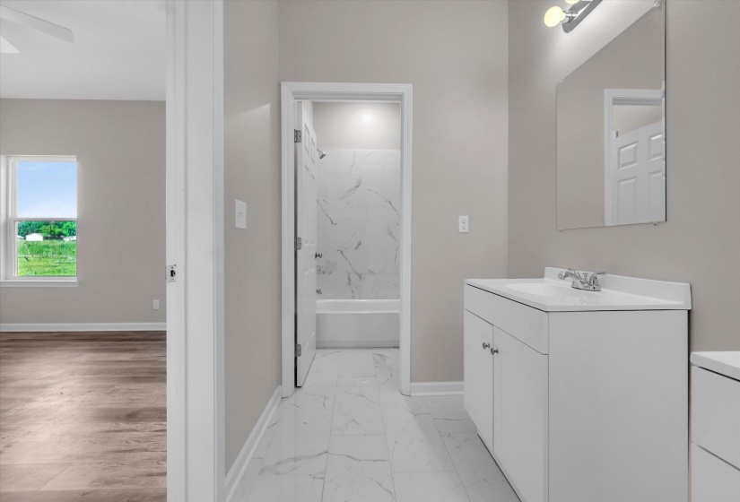 Bathroom featuring a white vanity with integrated sink, chrome faucet, and rectangular mirror