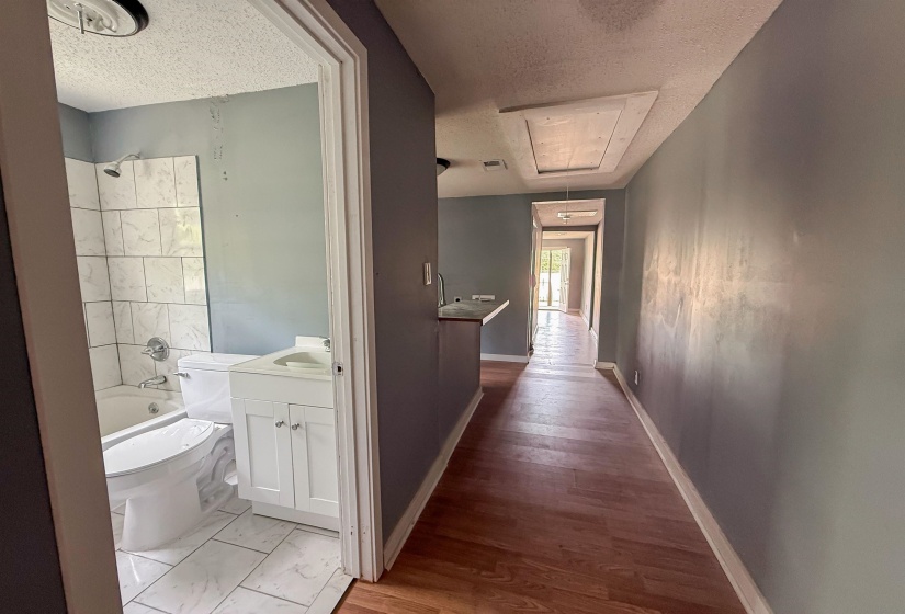 Bathroom featuring a white vanity with cabinet storage, a white bathtub with tile surround, and a white toilet
