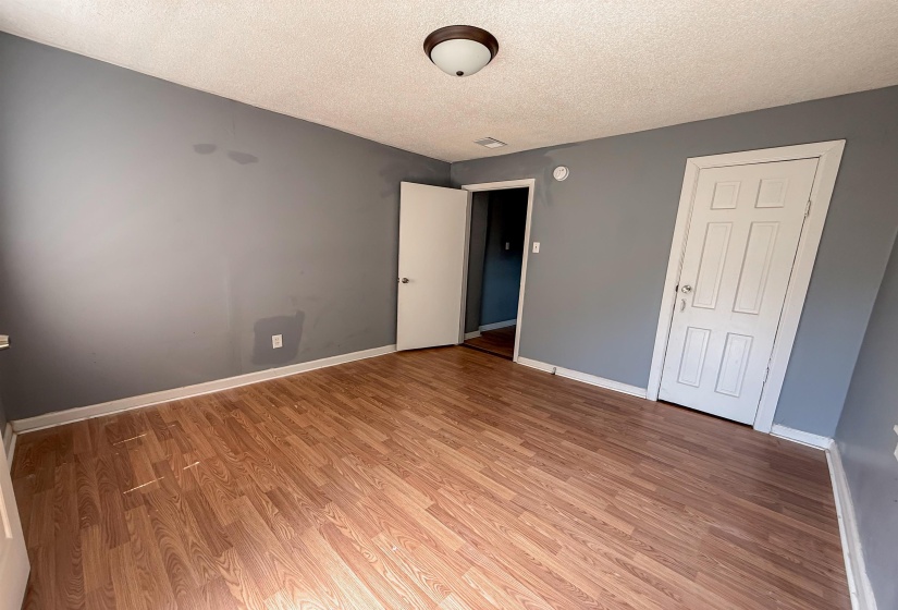 Spacious room featuring wood-finish flooring, light gray walls, white baseboards, and a semi-flush mount ceiling light fixture