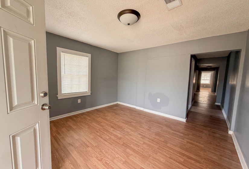 Room featuring wood-finish flooring, a window with blinds, and neutral grey wall paint