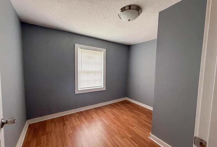 Room featuring wood-finish flooring, a window with blinds, and a ceiling-mounted light fixture