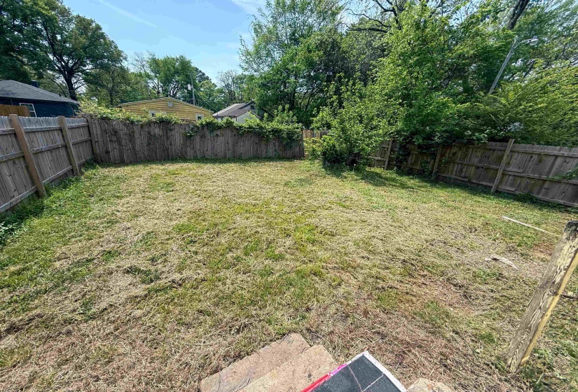 Spacious fenced backyard featuring a level lawn and mature perimeter trees