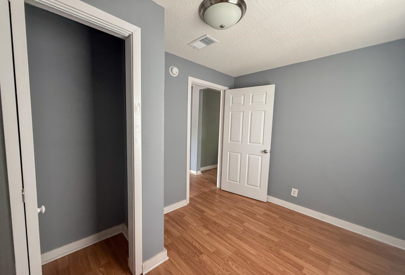 Room featuring wood-finish flooring, painted walls, white trim, and a ceiling-mounted light fixture