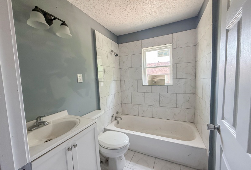 Bathroom featuring a white vanity with cabinet storage, a white toilet, and a white bathtub