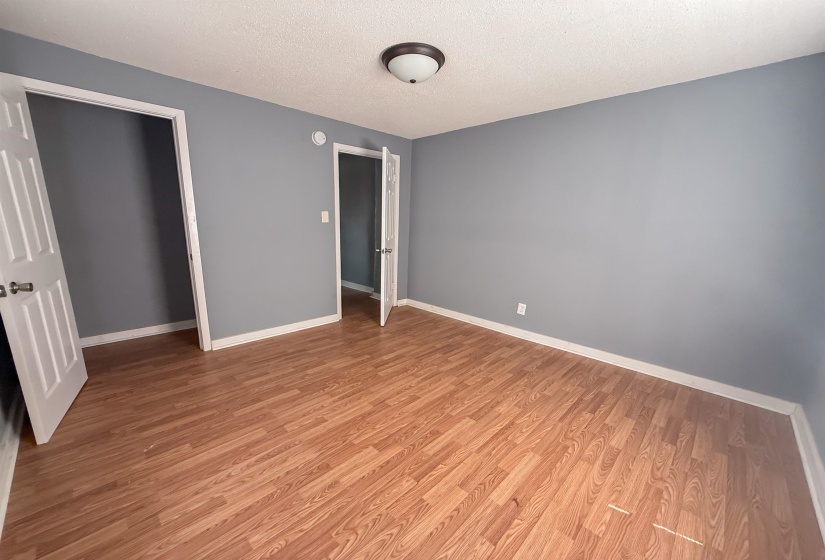Interior space featuring wood-finish flooring, gray walls, white baseboards, and white paneled doors