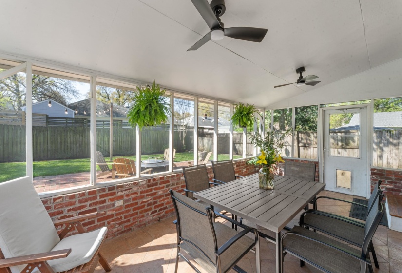 Screened in porch with outdoor dining area and ceiling fan.