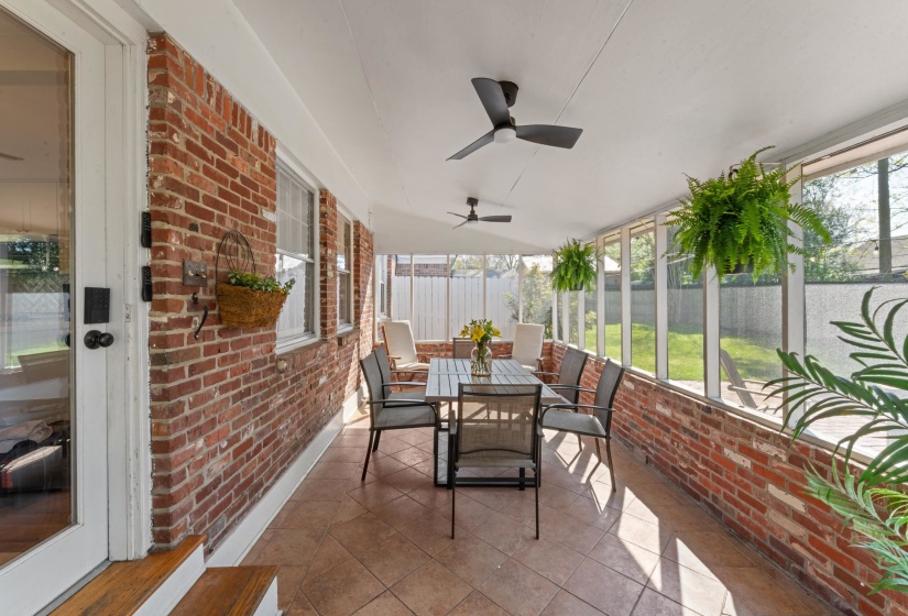 Screened in porch with outdoor dining area and ceiling fan.