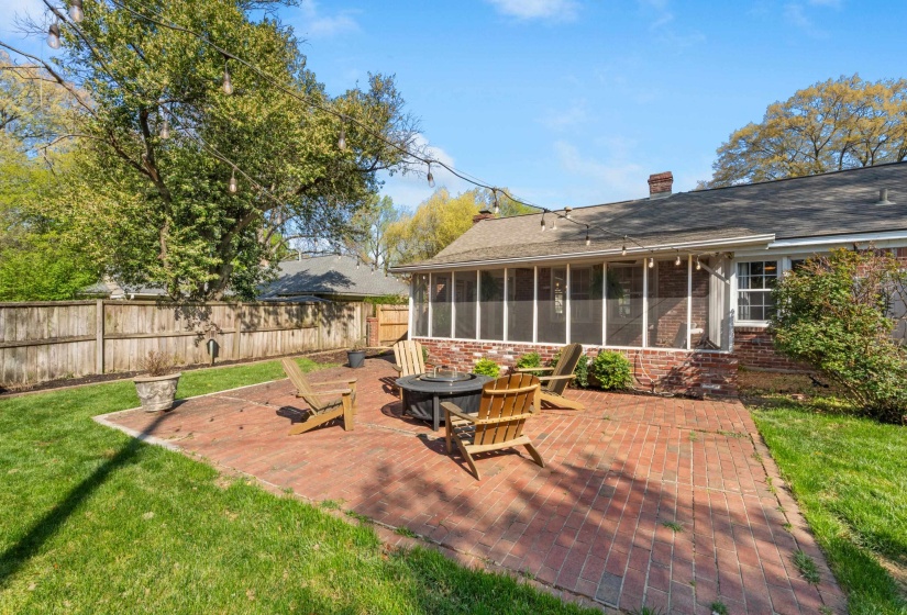 Back of house featuring a patio, a sunroom, a chimney, and brick siding