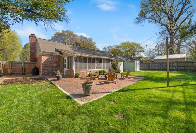 Back of house with a sunroom, a patio area, a storage shed, a fenced backyard, and a chimney