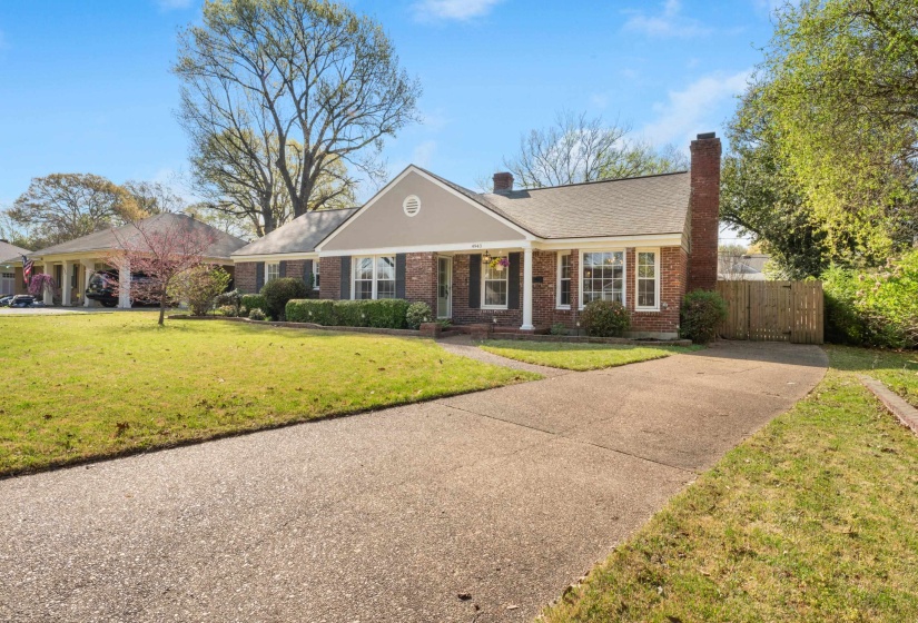 View of front of house featuring a porch, brick siding, a chimney, driveway, and roof with shingles