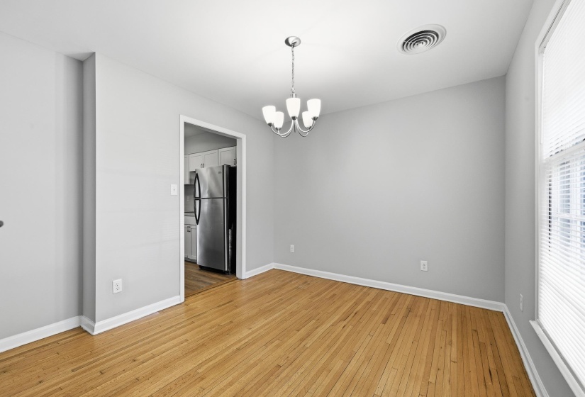 Hardwood flooring throughout, featuring a modern ceiling light fixture, neutral wall colors, and white trim