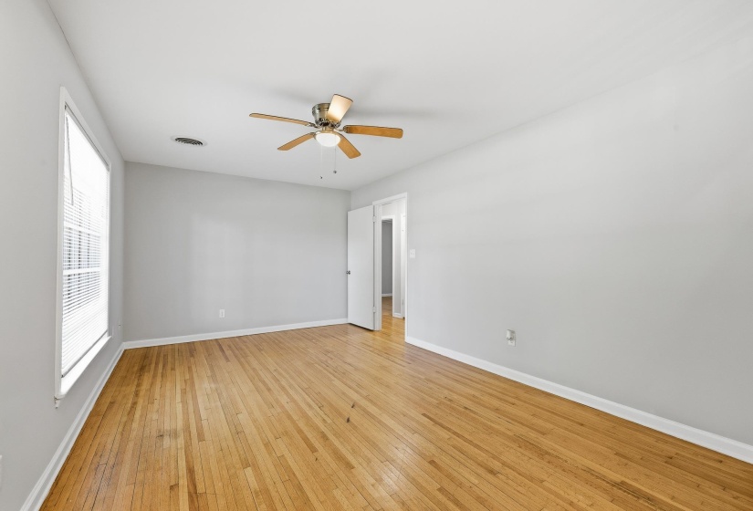 Room featuring wood-finish flooring, a ceiling fan with light kit, and neutral wall paint