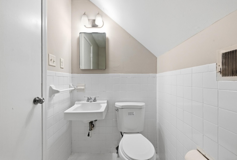Bathroom featuring white ceramic wall tiling, a wall-mounted sink, and a toilet