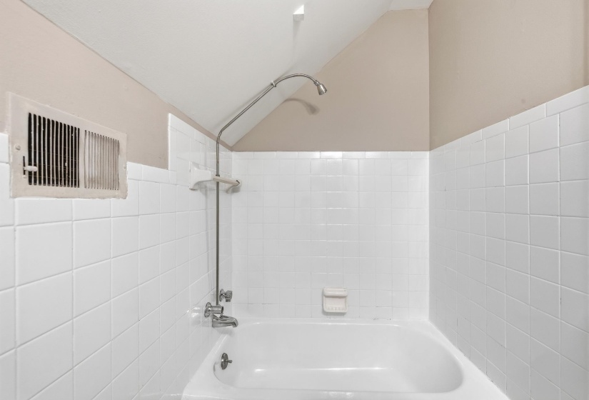 White tiled bath and shower combination with chrome fixtures