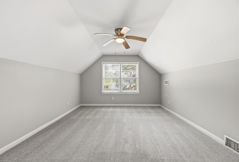 Spacious room featuring vaulted ceilings, light gray wall paint, and gray carpeting