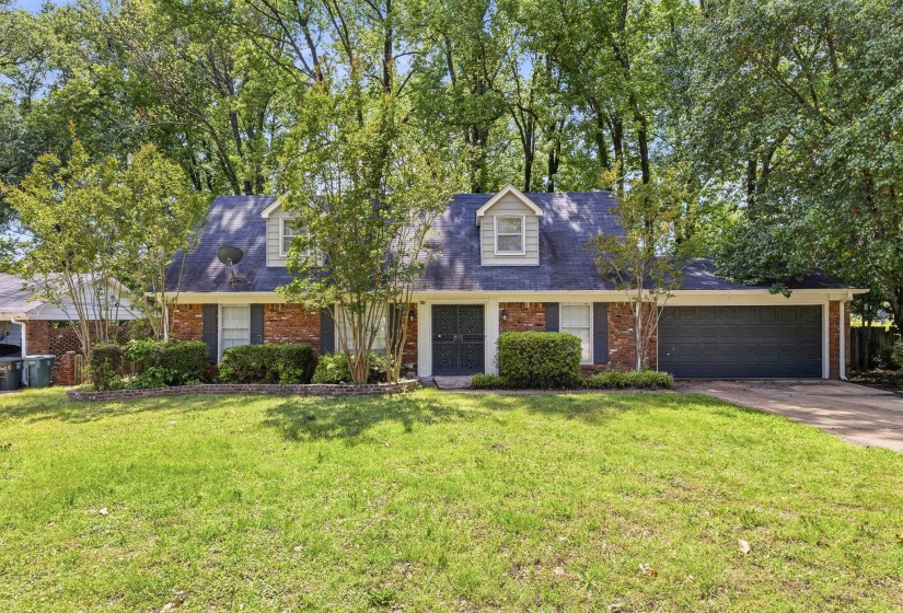 Traditional-style residence featuring a brick facade, dark gray roof, and two dormer windows