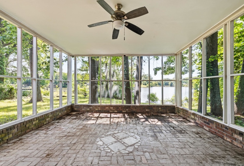 Screened porch featuring a natural brick flooring, a decorative stone inlay, and a ceiling fan with light fixture