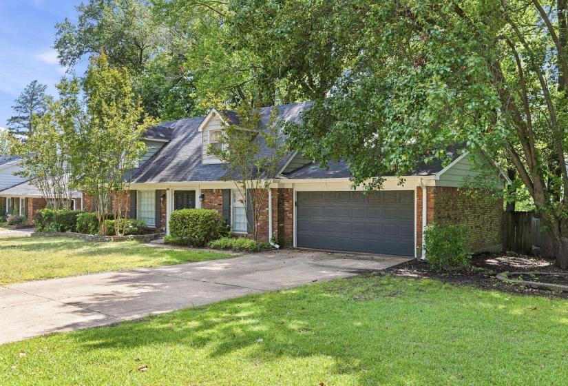 Brick and siding exterior featuring a dark asphalt shingle roof, a two-car garage with a gray door, and established landscaping
