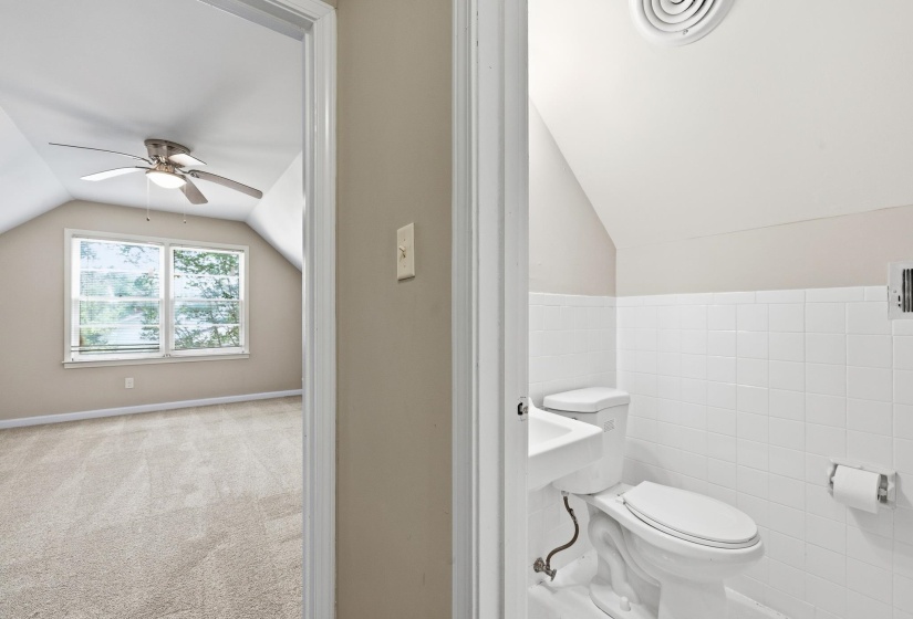 Carpeted room featuring a ceiling fan, window, and sloped ceiling