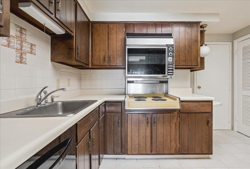 Kitchen featuring wood cabinetry, white countertops, stainless steel sink with chrome faucet, and integrated wall oven with cooktop