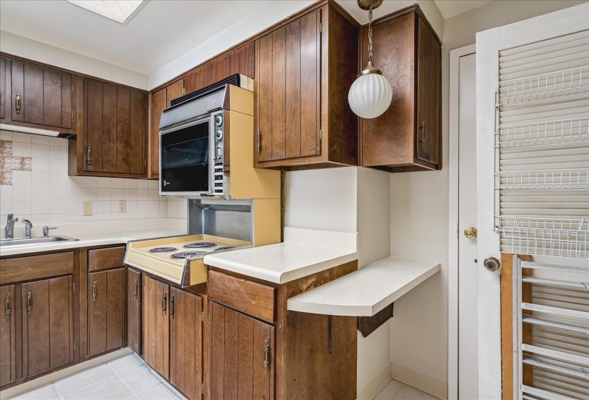 Kitchen featuring wood cabinetry, white countertops, a built-in oven, and a cooktop