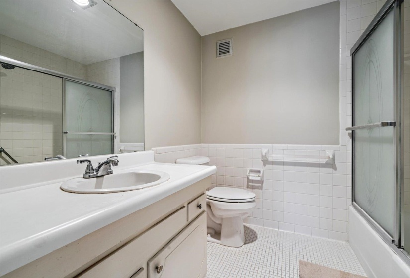 Bathroom featuring a single vanity with an integrated sink, chrome faucet, and expansive wall mirror