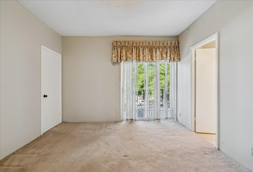 Carpeted room with a sliding glass door featuring sheer curtains and a decorative valance