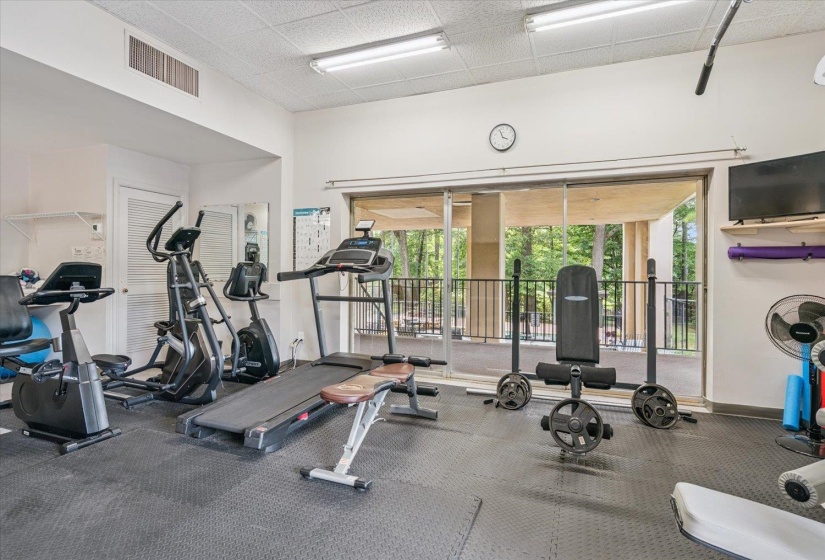 Dedicated fitness area featuring rubber flooring, recessed lighting, and a large sliding glass door with balcony access